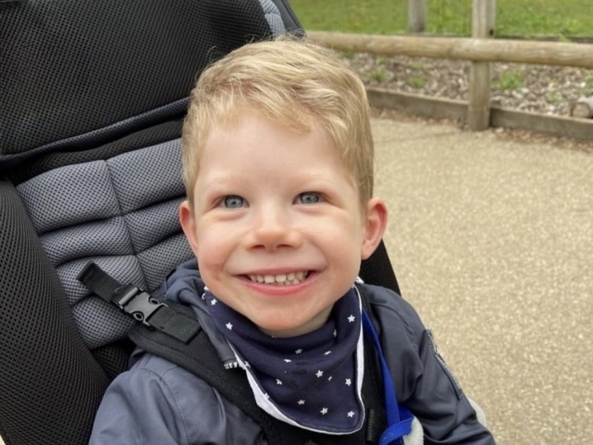 A young mito patient outside in a buggy smiling at the camera