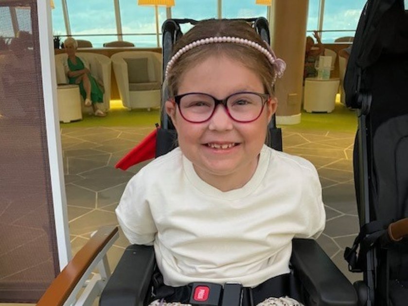 A young mito patient wearing glasses and a white t-shirt sitting in a wheelchair