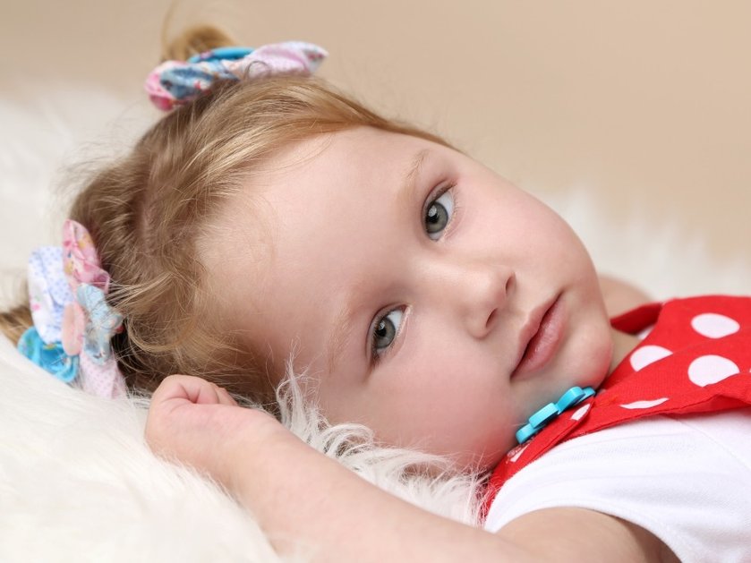 Close-up of a young mito patient lying on a fluffy run looking sideways towards the camera