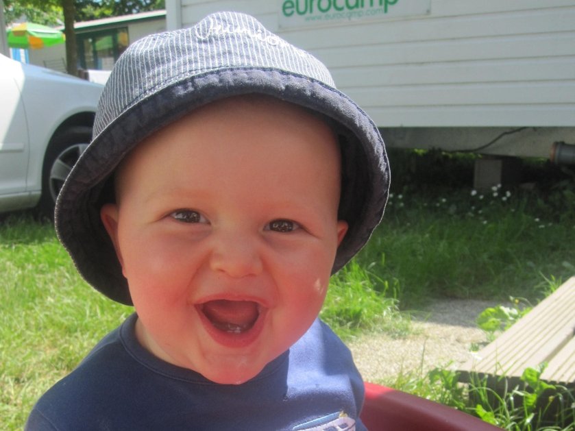Close-up of a young boy wearing a sunhat and sitting in the garden