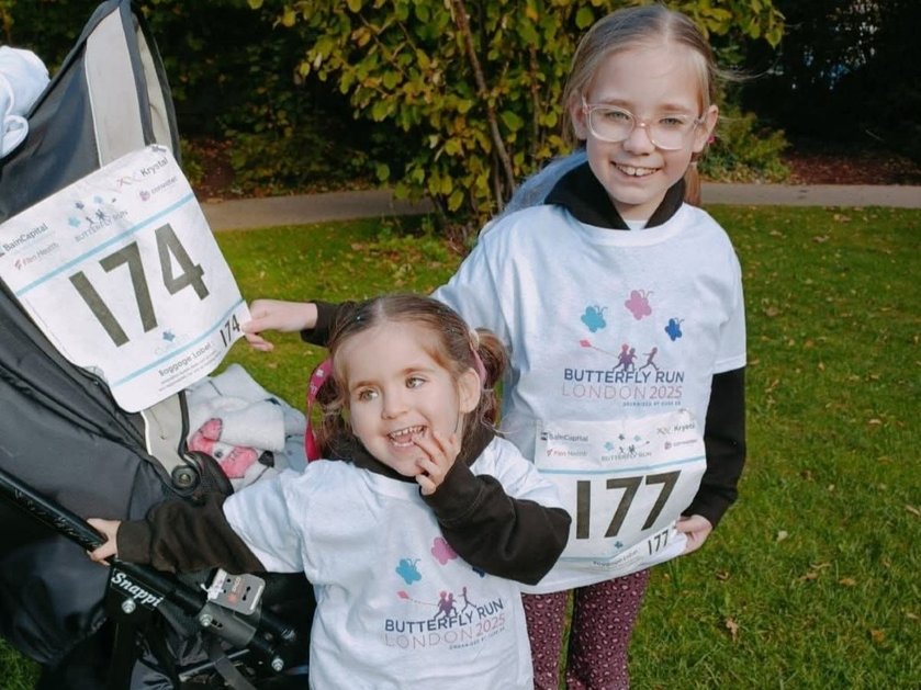Two young girls wearing running numbers for the Butterfly Run and laughing