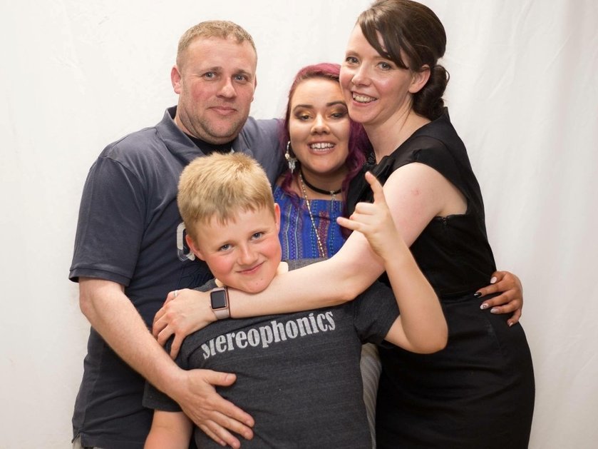 A family group smiling with their arms around each other
