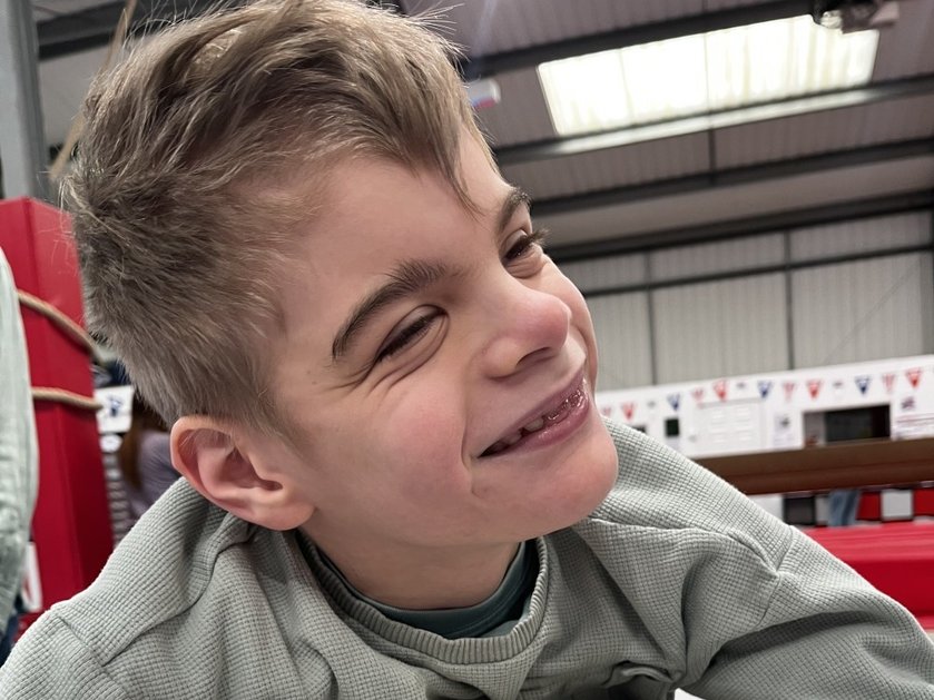 Close-up of a young mitochondrial disease patient with blonde hair smiling