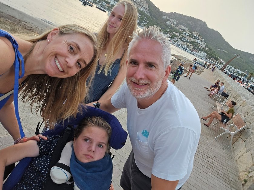 Mito patient Poppy and her family standing at the seaside together smiling