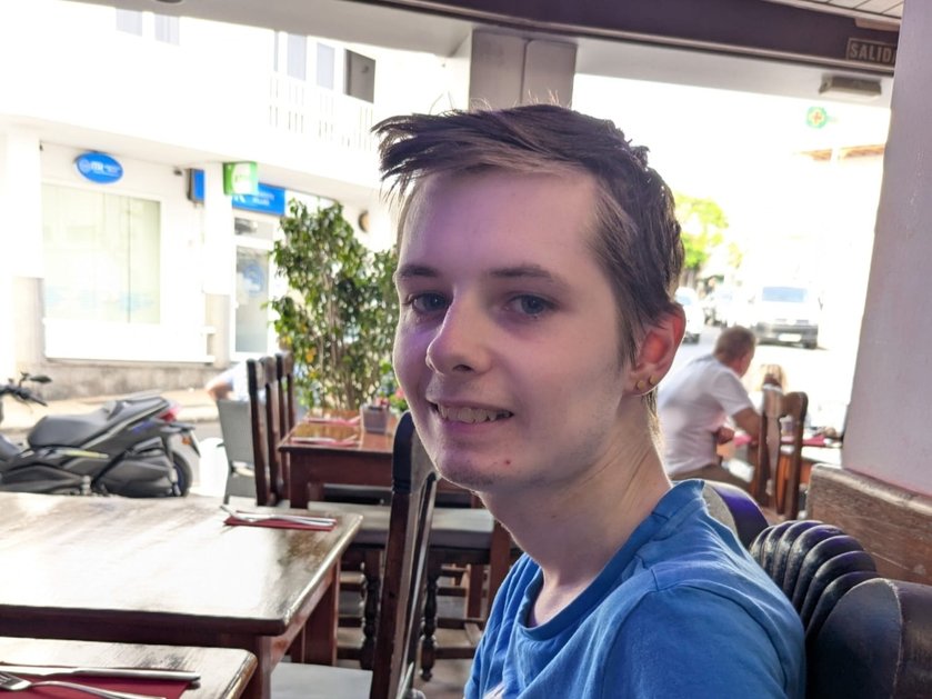 A young mito patient in a blue t-shirt looking to the side and smiling