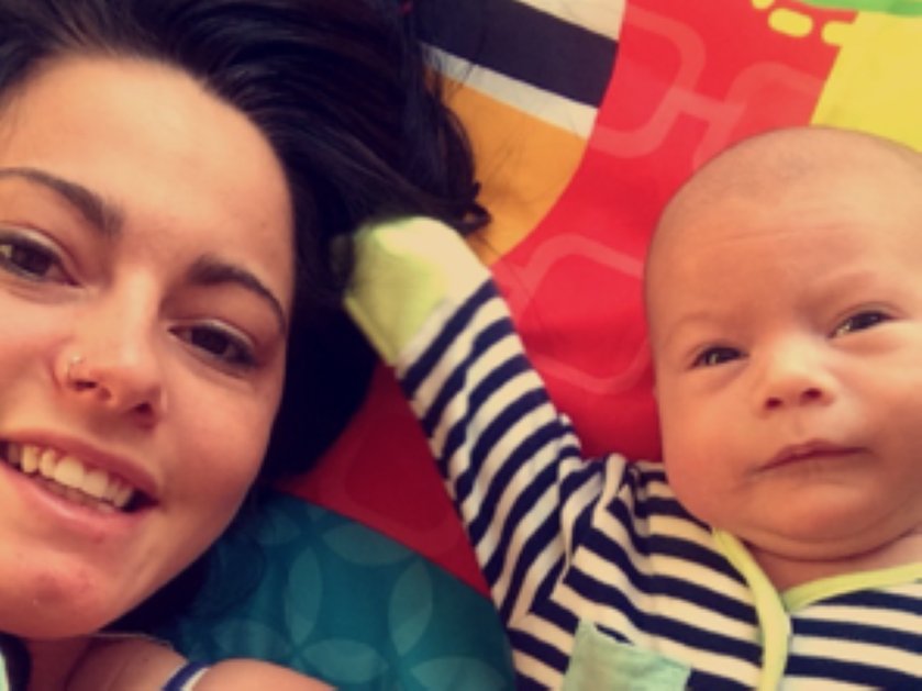 A mum lying down next to her small baby who has mitochondrial disease