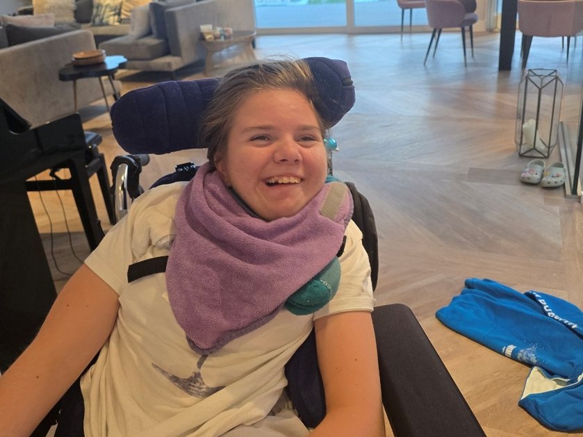 Mitochondrial disease patient Poppy laughing in a wheelchair