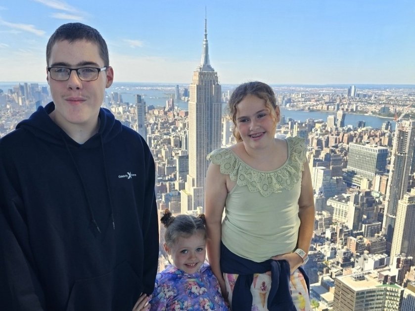 A young mito patient stands with his two sisters in front of the New York skyline