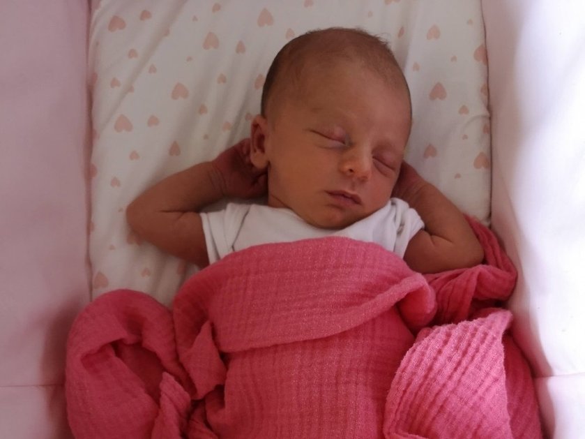 A tiny baby with mitochondrial disease asleep wrapped in a pink blanket