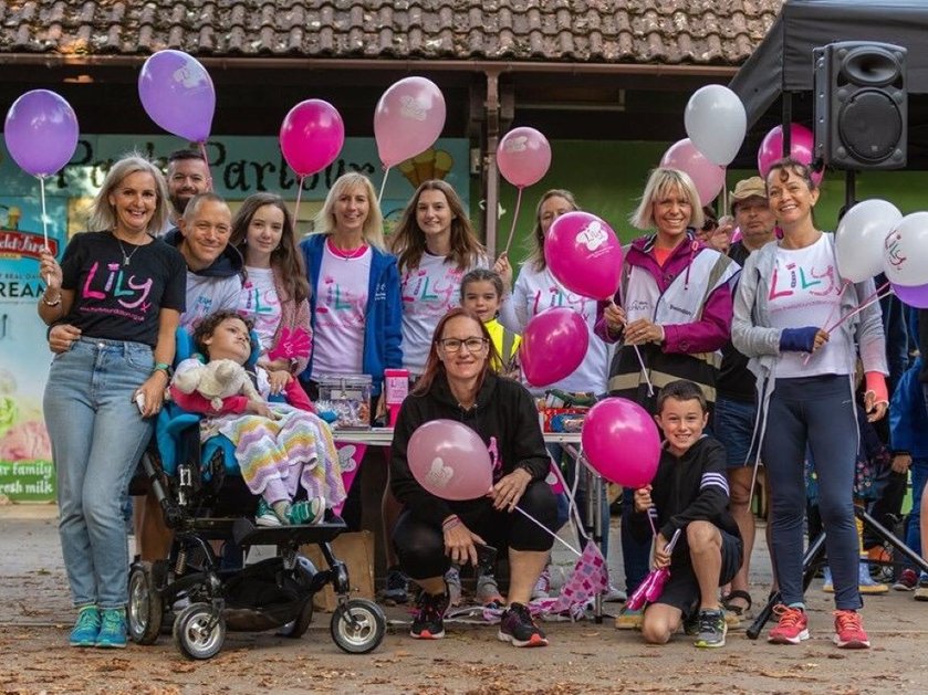 A group of people standing together holding balloons and wearing Lily tops