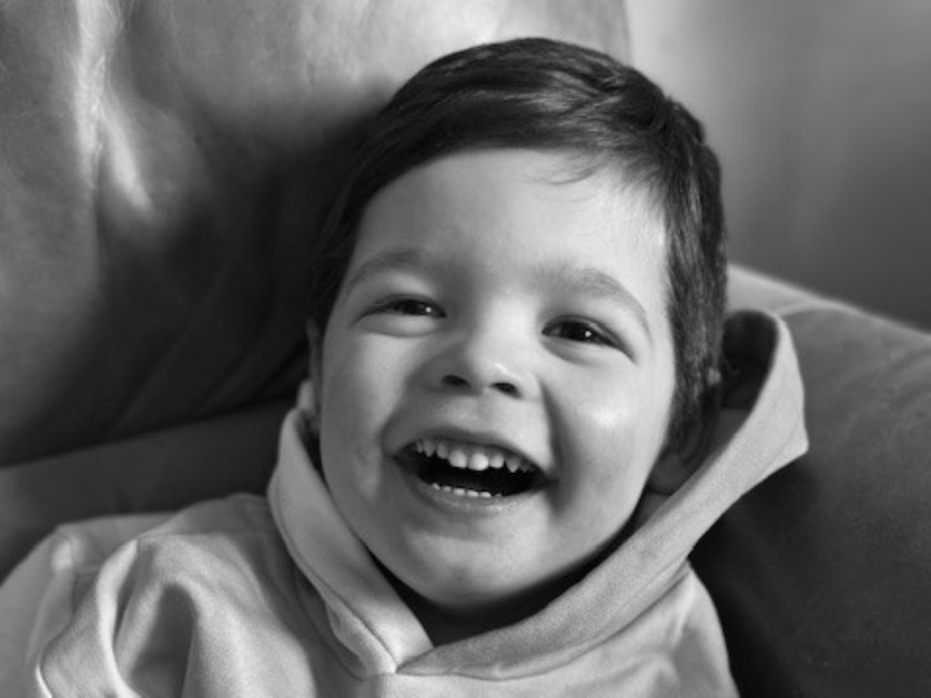 Black and white image of a young mito patient wearing a hoodie and laughing