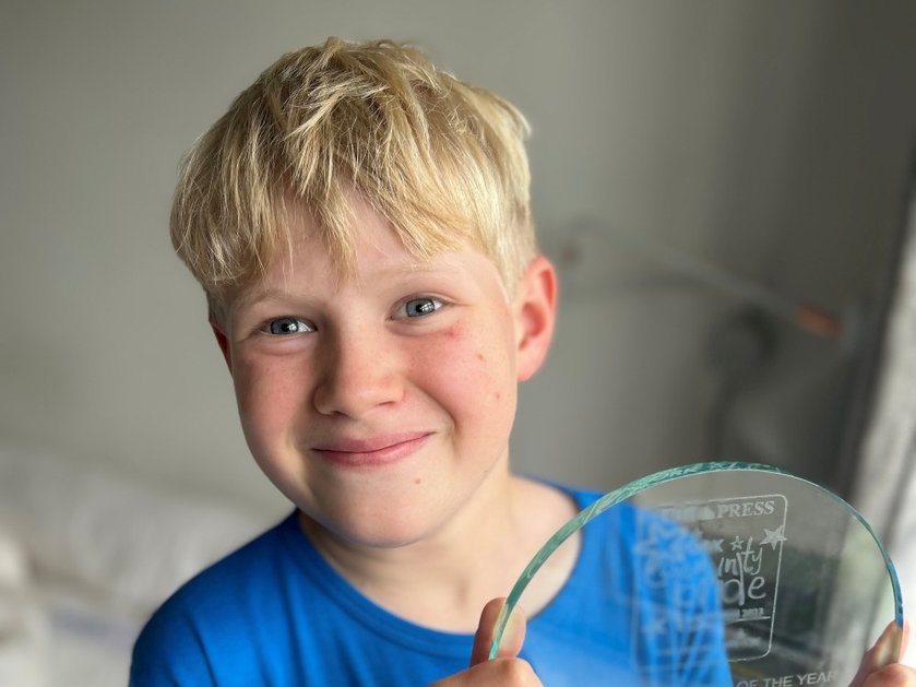Mitochondrial disease patient Bill smiling and holding up a glass trophy