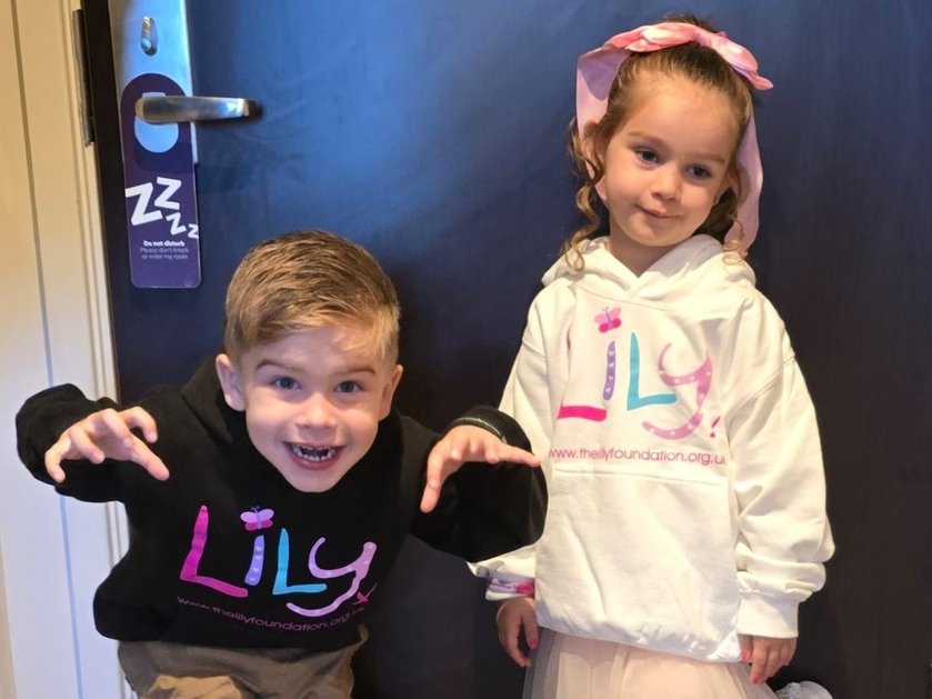 Two young mito patients wearing Lily hoodies and posing in front of a door