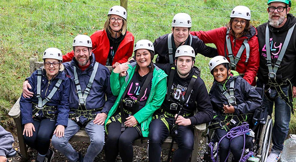 Lily volunteers and young adults with mitochondrial, in orienteering gear about to zip wire in the Lake District
