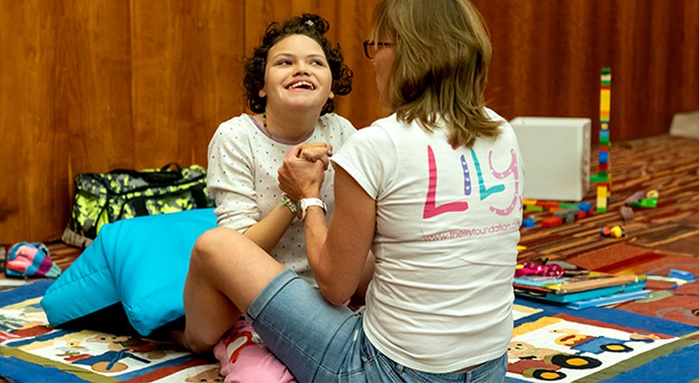 Happy girl with mito engaged in play with her carer at The LIly Foundation family support weekend