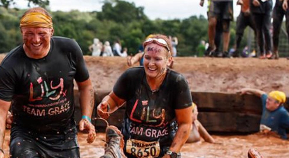 Four Lily Fundraisers, laughing, covered in mud at a Tough Mudder event