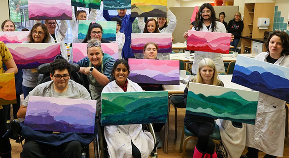 Group of young adult mito patients holding up their colourful paintings of the lake District
