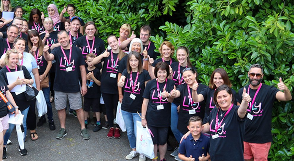 Looking down on a big group of LIly volunteers, all wearing LIly Tshirts and waving up at the camera