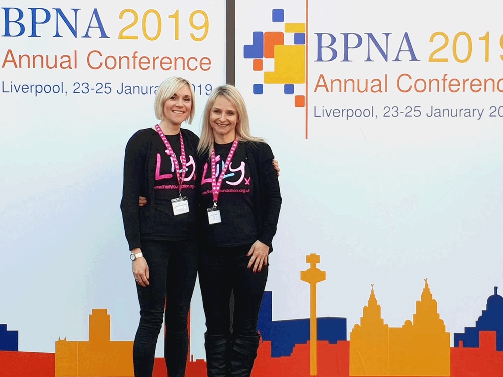 Two members of the Lily Foundation team stand infront of a BPNA sign