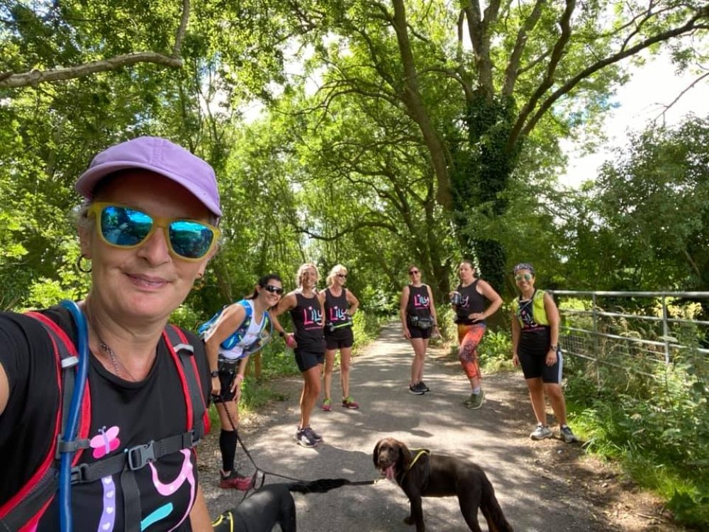 A group of supporters in Lily Foundation tops walking down a shady tree-lined lane