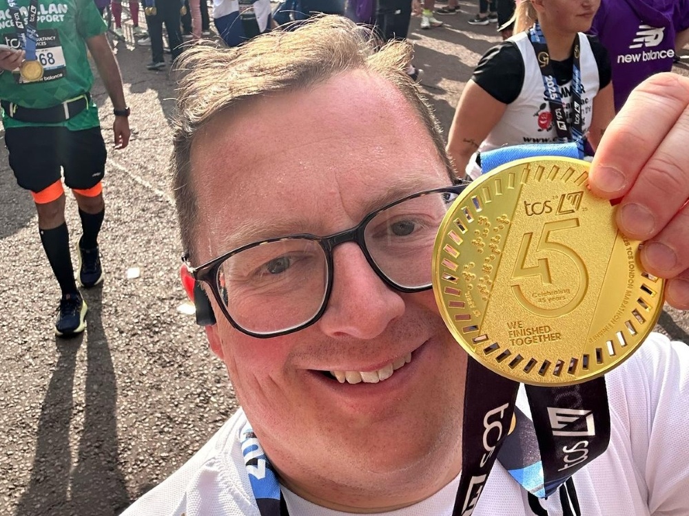 A Lily Foundation runner proudly holds his London Marathon medal up