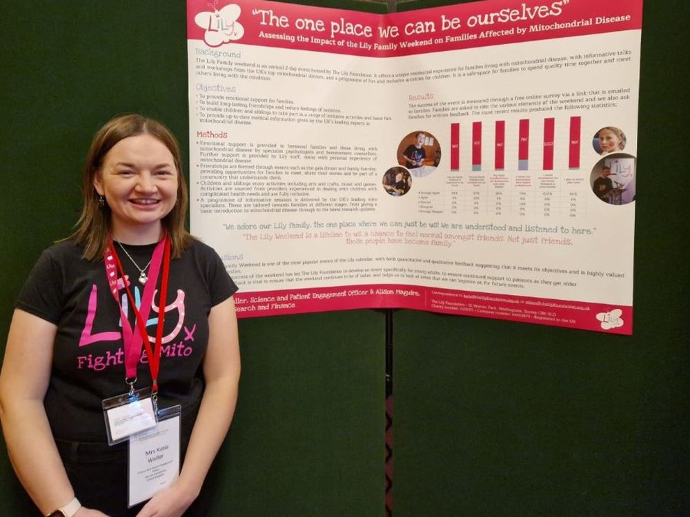 A woman stands in front of a large poster which has the title The One Place We Can Be Ourselves