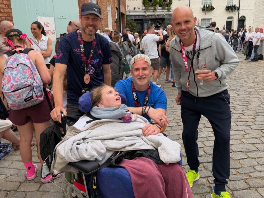 Mito patient Poppy in her wheelchair with her family gathered round with London marathon medals