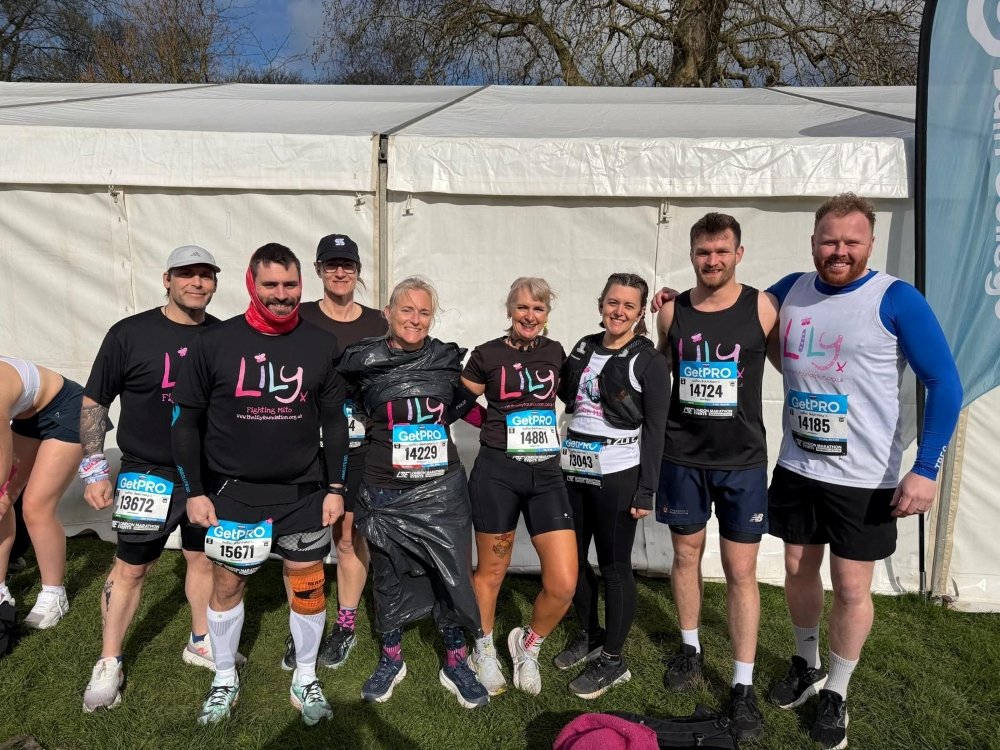 A group of runners wearing Lily tops standing arm in arm after completing a race