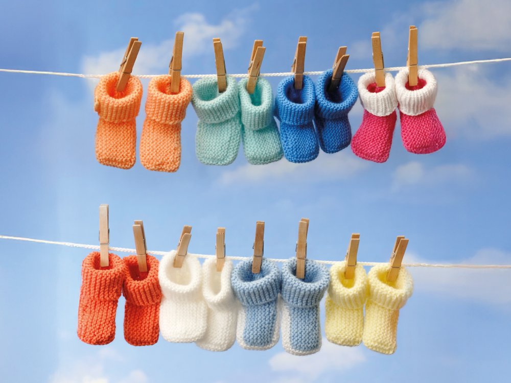 From law change to life-changing results - Eight pairs of baby bootees in bright colours hanging on a washing line