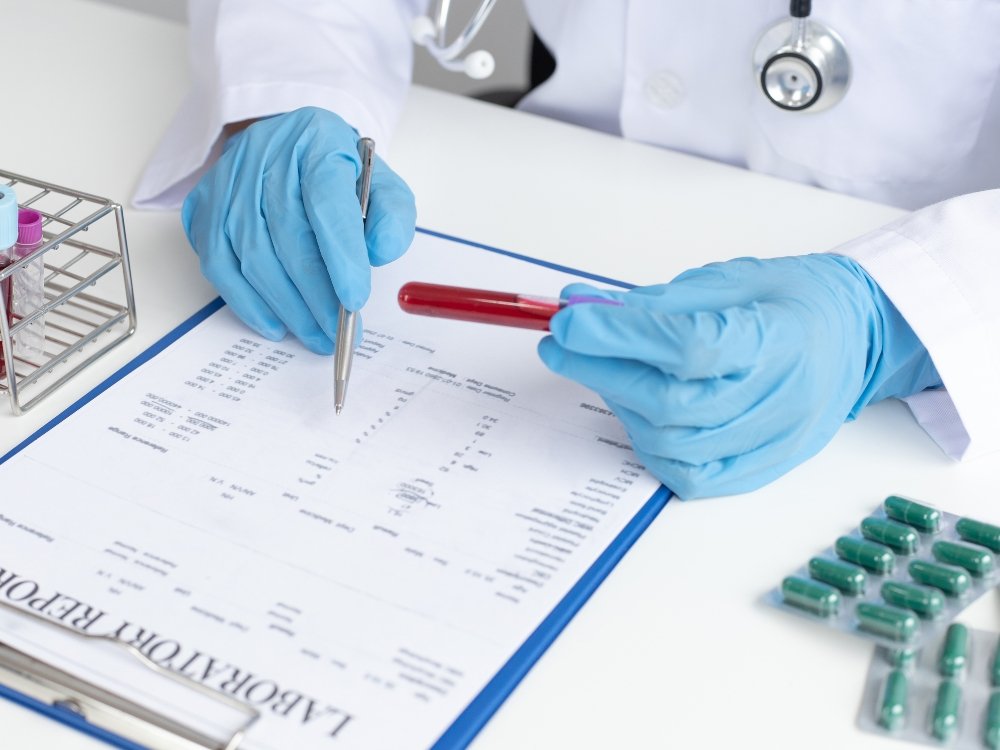 A person wearing protective gloves looking at samples in a test tube with a clipboard in front of them