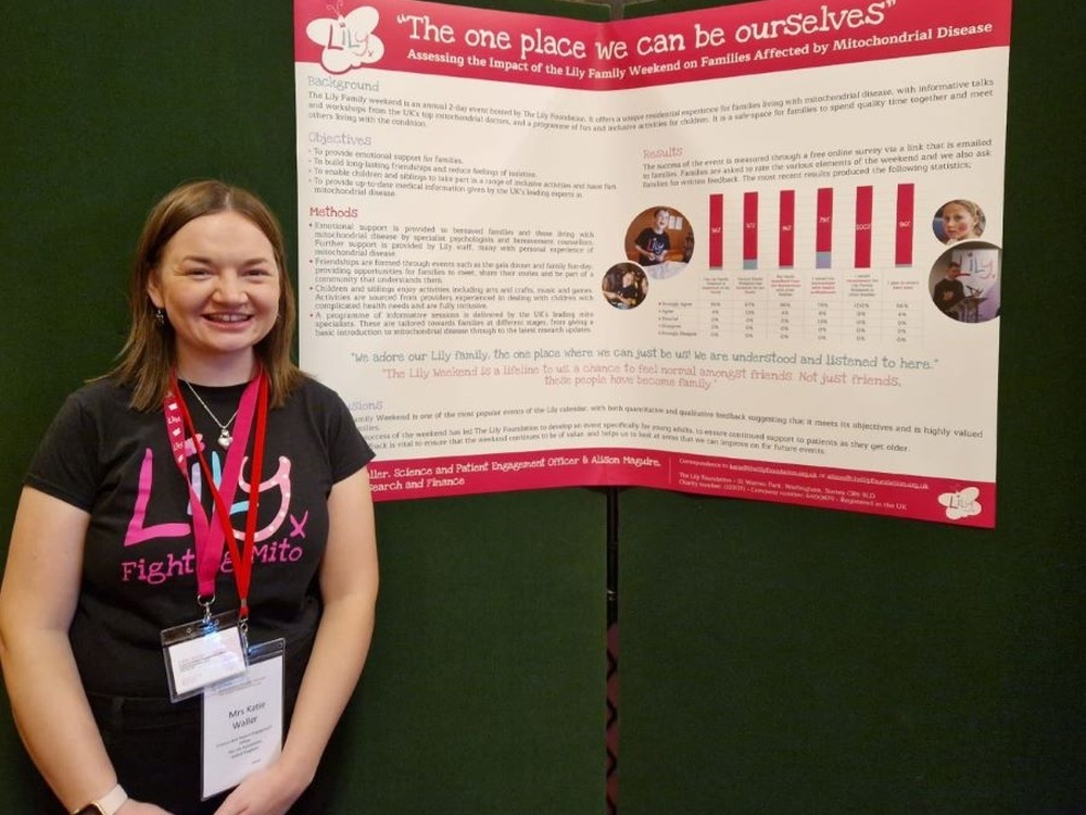 A woman stands in front of a large poster which has the title The One Place We Can Be Ourselves