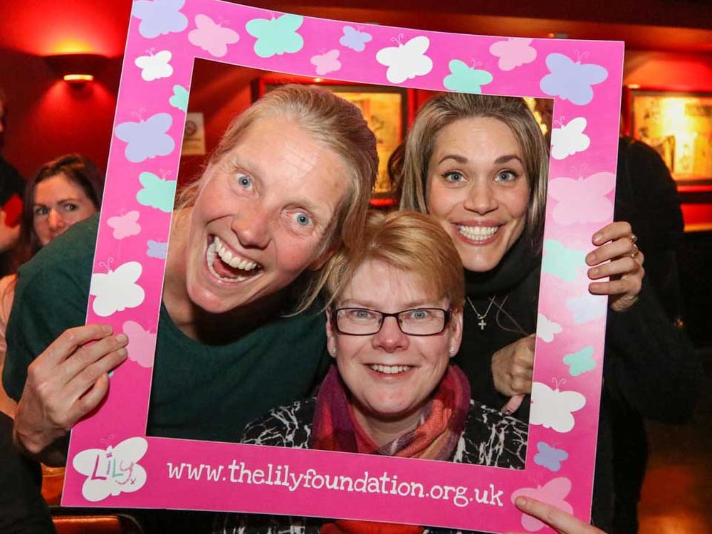 Three people smiling through a frame covered in Lily foundation butterflies