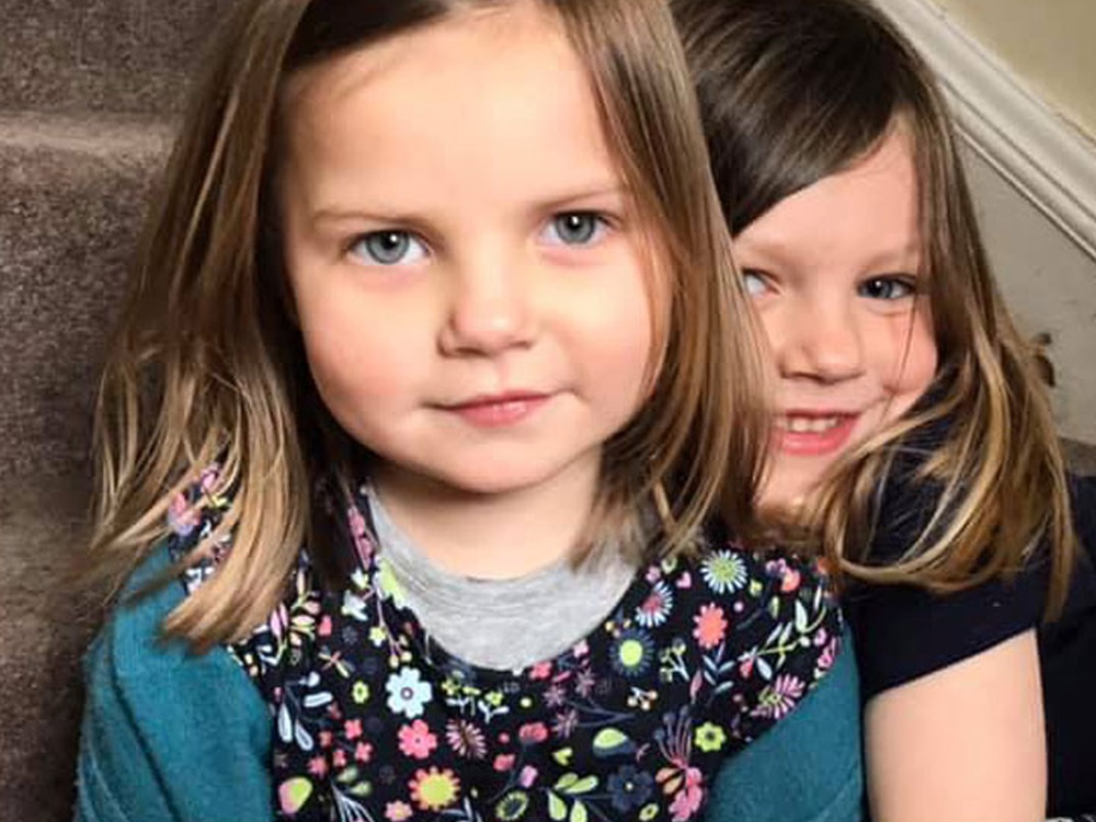 two little girls holding each other look into the camera