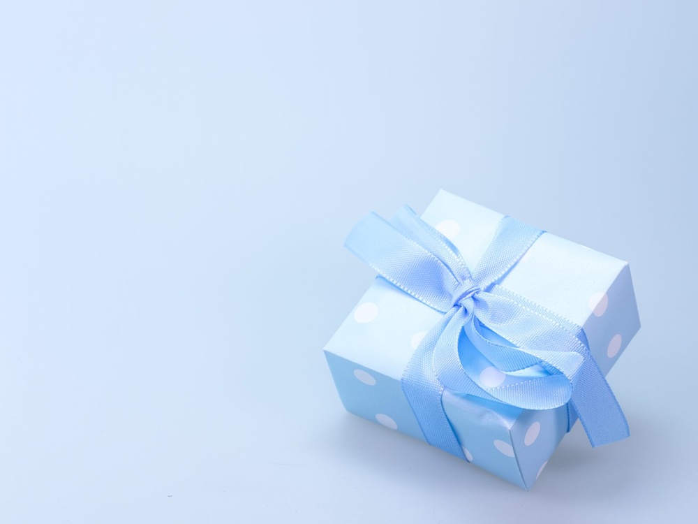 A box wrapped in pale blue paper with white spots and a blue ribbon tied in a bow