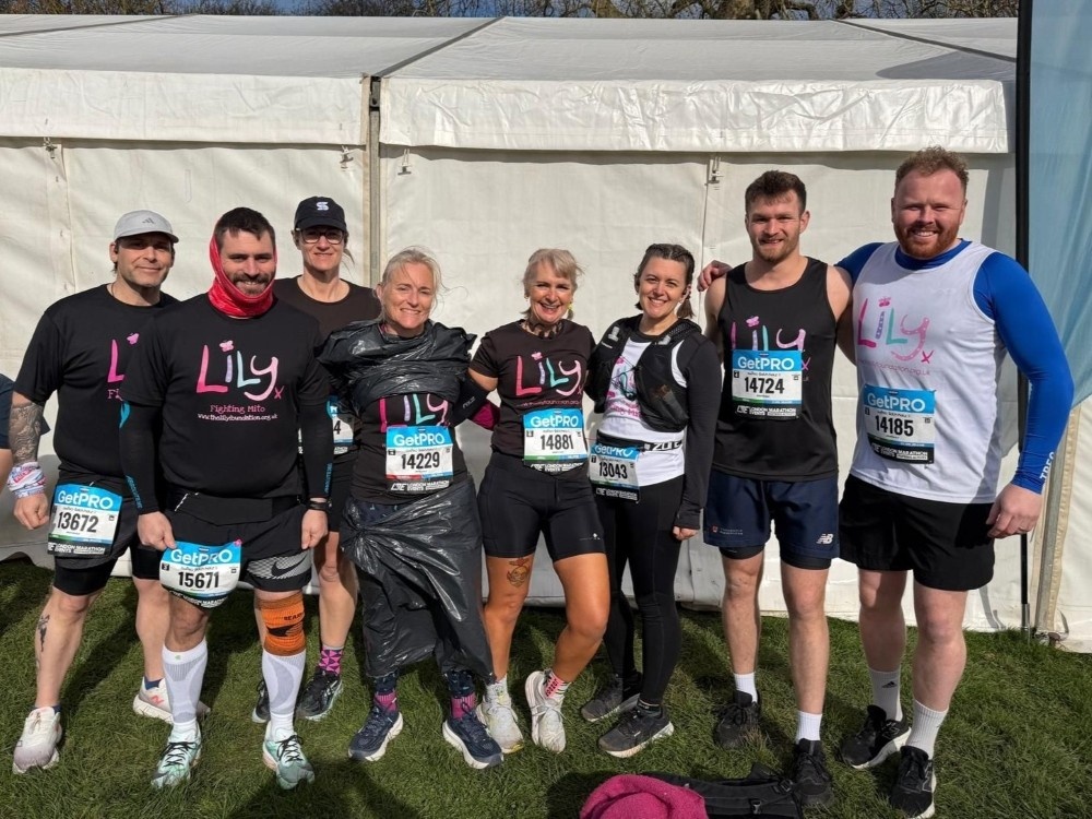 A group of runners wearing Lily tops standing arm in arm after completing a race
