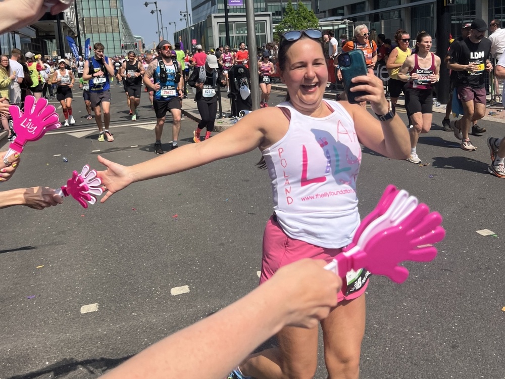 A lady running the London Marathon and laughing with spectators on the sidelines