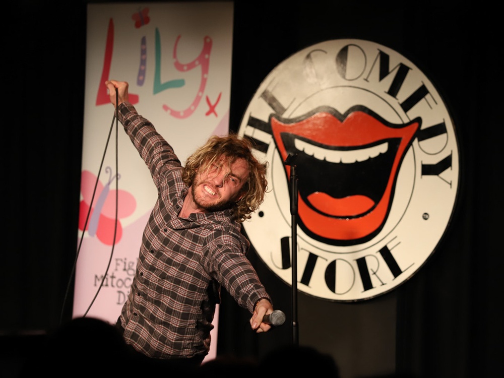 Comedian Seann Walsh waving his arms around on stage at the Comedy Store
