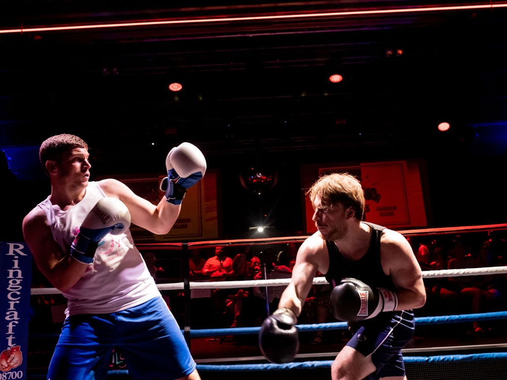Two male boxers in Lily vest throwing punches in the ring