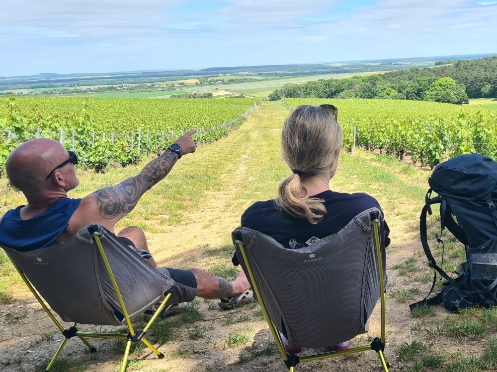 Two hikers in Lily Foundation tops sitting looking out a the fields stretched out ahead of them