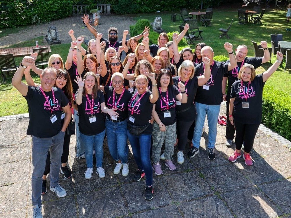 A group of people in Lily Foundation tops outside smiling and fist pumping in the air