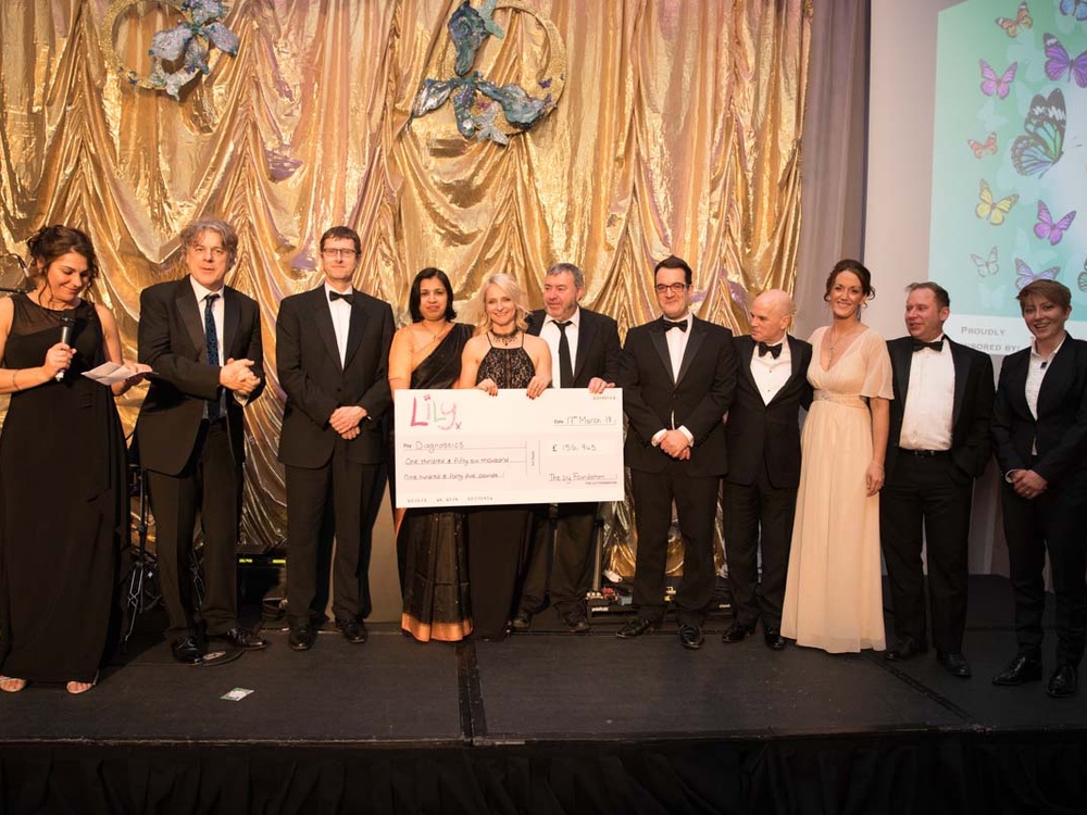 A group of people lined up on stage with one holding an oversized cheque