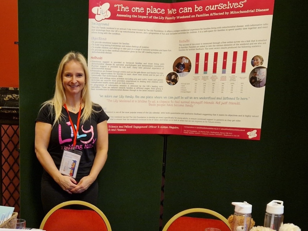 A member of Lily Foundation staff stands behind an information stand covered with leaflets