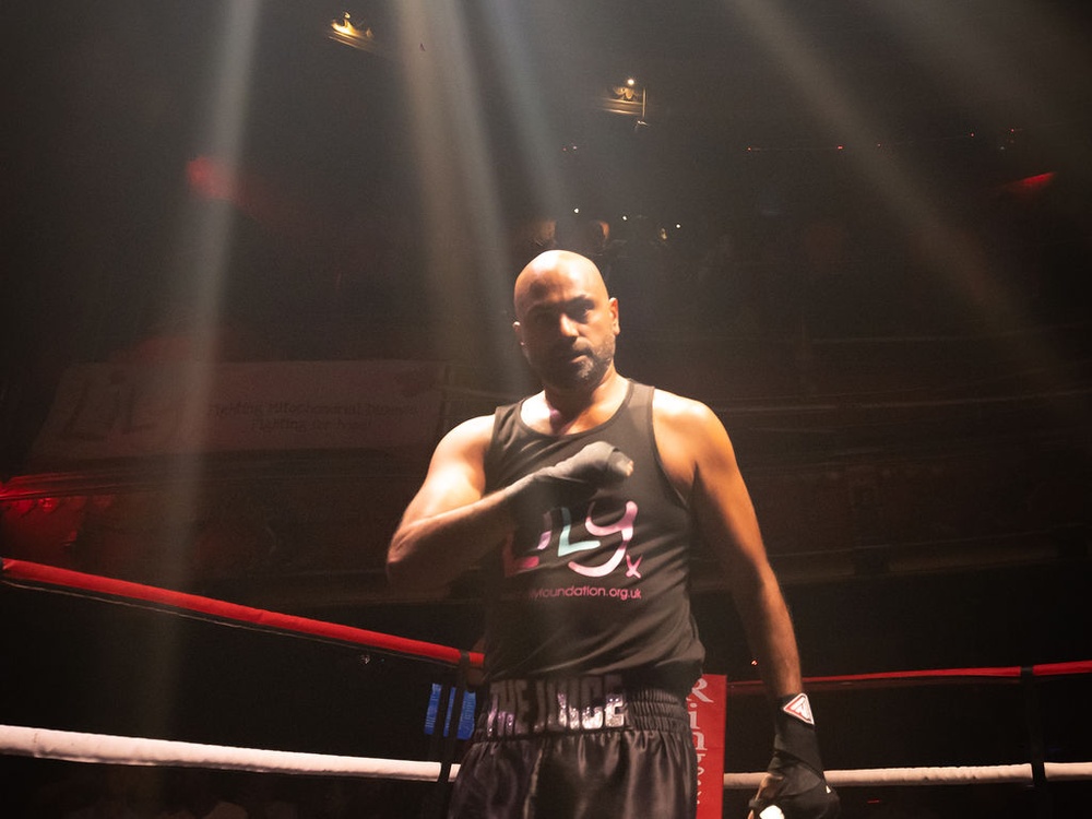 A male boxer in a Lily vest pressing his hand to his heart