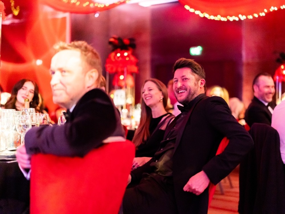 A group of people sitting at a table at the Lily Foundation ball laughing