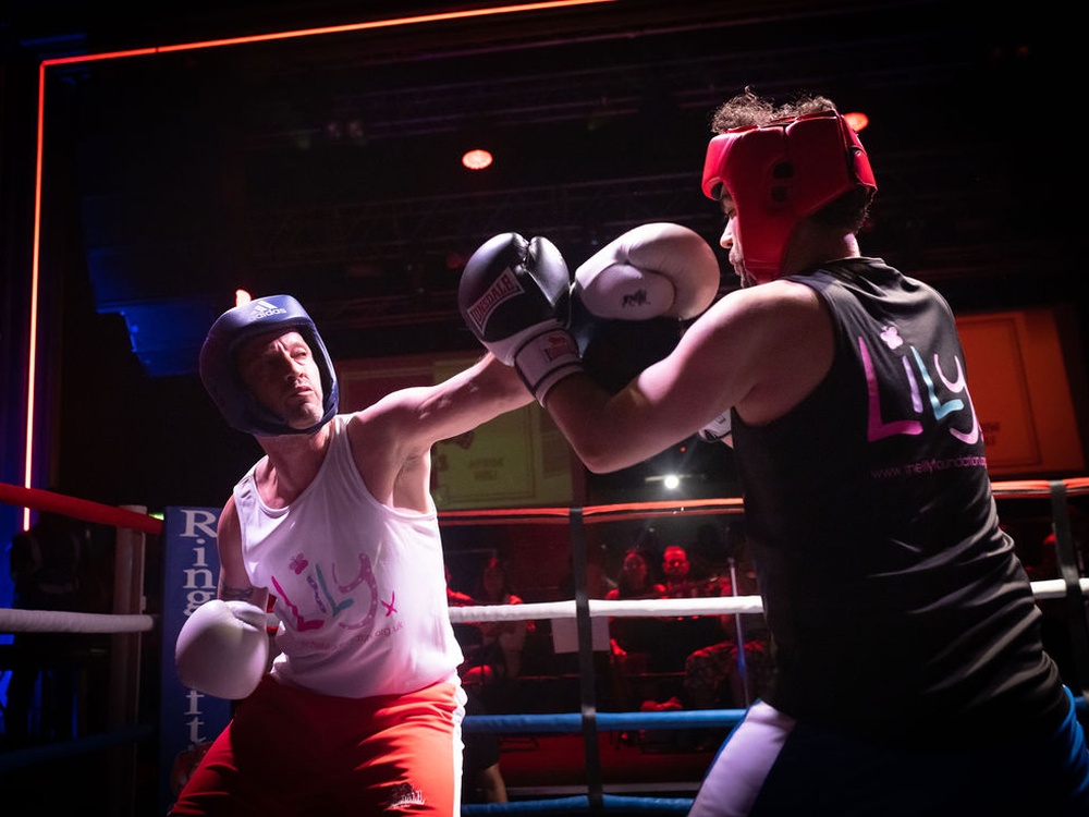 Two men in Lily tops throwing punches in the ring