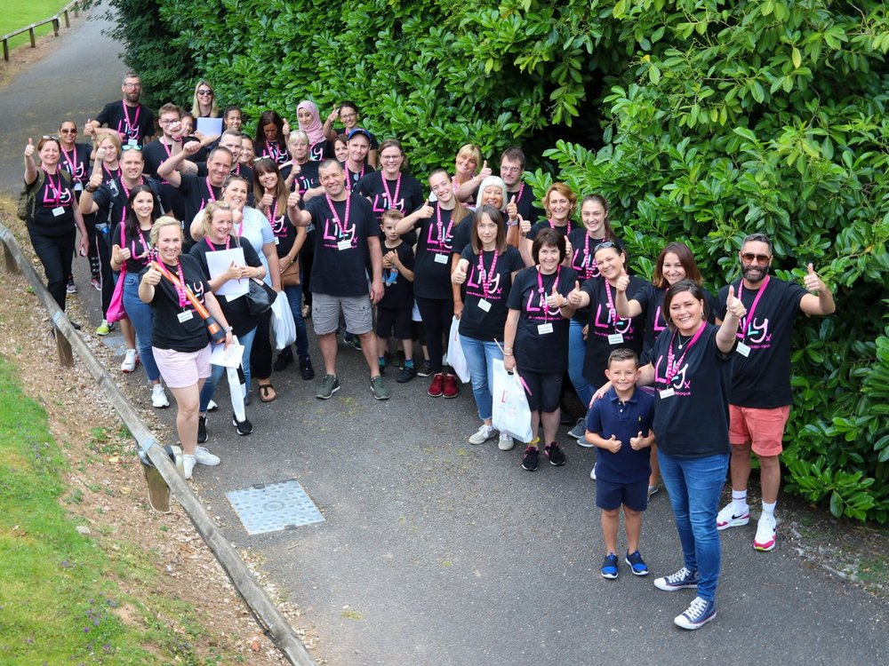 Celebrating 15 years of… volunteering - A large group of Lily Foundation staff and volunteers looking up at the camera and smiling with their thumbs up