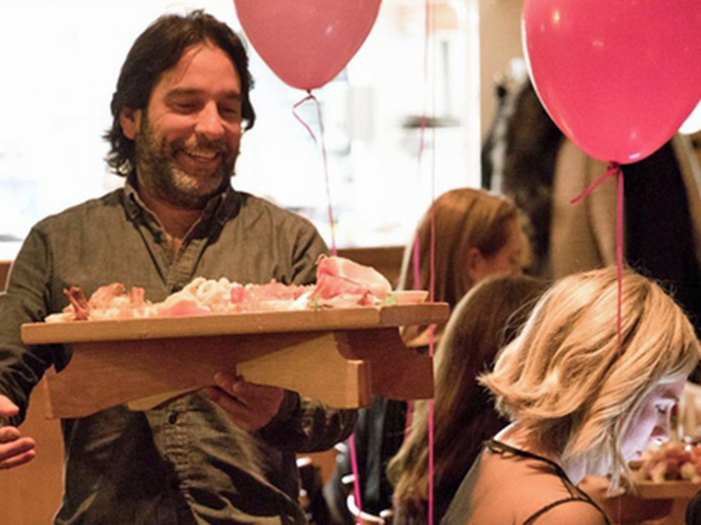 Lily Italian Night at Bagatti's, 2nd Nov 2021 - A man with shoulder length dark hair in a restaurant carrying a platter of food with pink Lily balloons in the background