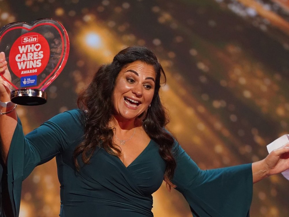Lily founder honoured at star-studded awards ceremony - Lily Foundation CEO Liz Curtis holding her Sun Who Cares Wins award, waving her arms and smiling