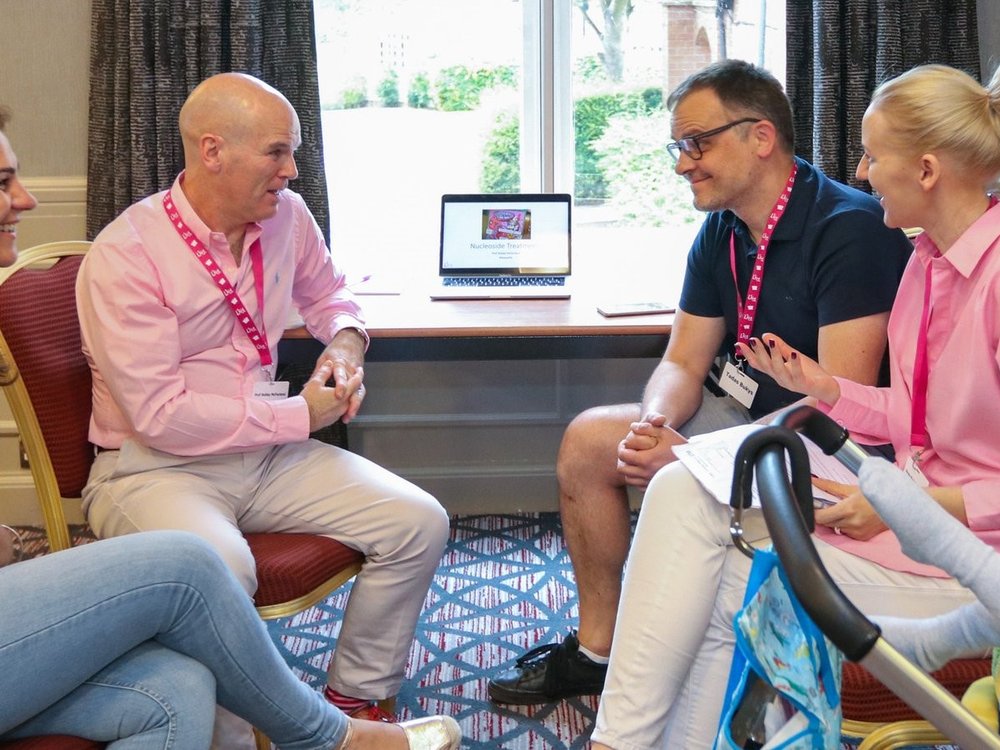 Celebrating 15 years of… patient advocacy - Two people sitting across from each other wearing Lily Foundation pink lanyards and talking