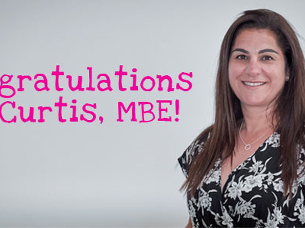 Liz accepts MBE on behalf of entire 'Lily Family' - Liz Curtis, Lily CEO and founder, standing next to a congratulations message